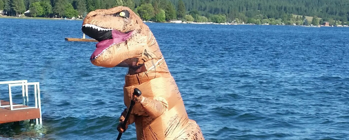Sarah (Allen) Caprye ’01 is a busy mother of five, with a part-time job as a dinosaur. Here she's pictured in the Spokanasaurus Rex costume on a paddle board. (Photo courtesy of Caprye)