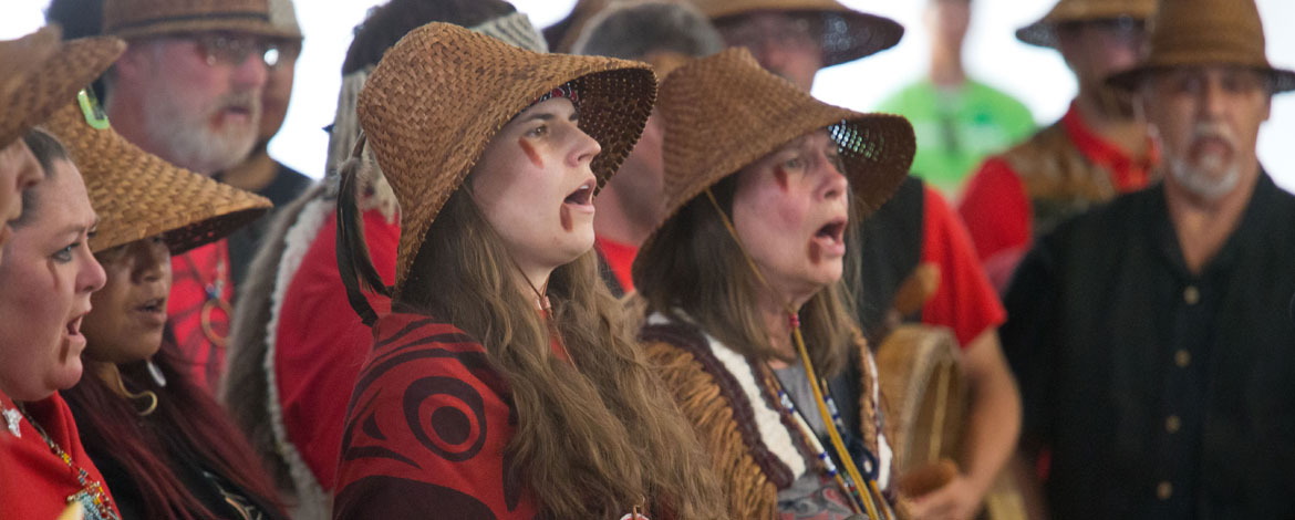 Kelly Hall '16, a language specialist with her tribe, sings alongside fellow Samish tribal members during protocol at the Power Paddle to Puyallup. The ceremony — during which tribes share songs, stories and dances — was part of the annual canoe journey. (Photo by John Froschauer/PLU)