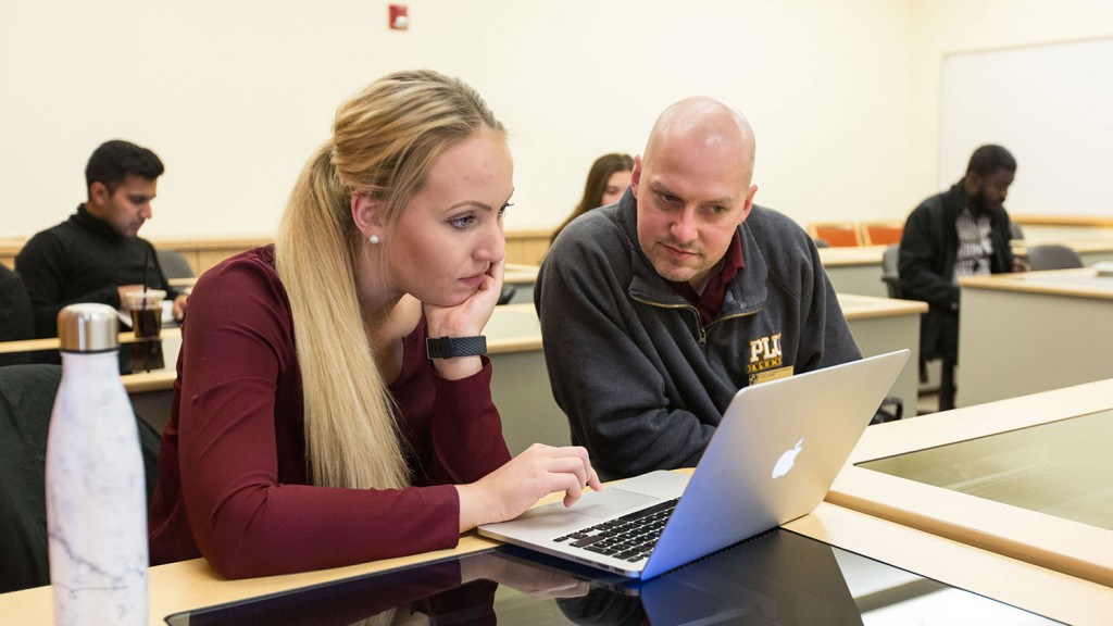 Dixon and Joreia lean over a laptop computer, making final notes before their capstone presentation.