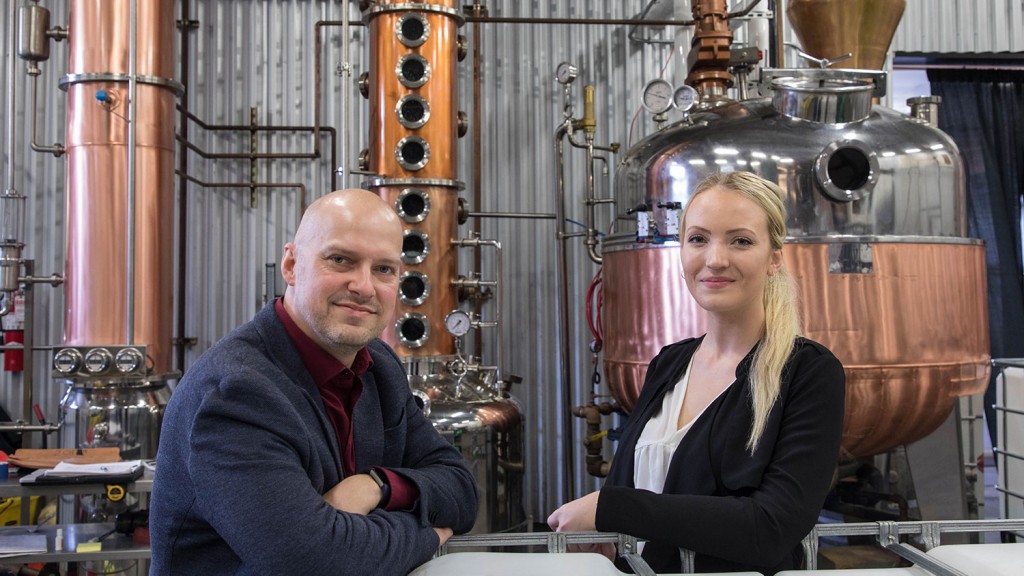 Dixon and Joreia pose in front of distilling machinery at HDC.