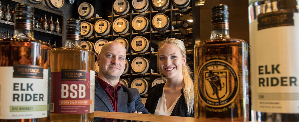 MSMA students Matthew Dixon ‘19 and Ingeborg Joreia ‘19 smiling in the middle of HDC craft spirit bottles.