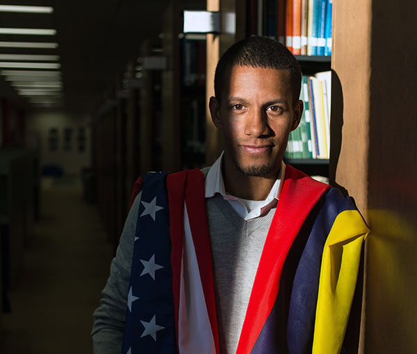 Jake Taylor '09 Standing in the library at PLU with the American and Colombian flags on his shoulders.