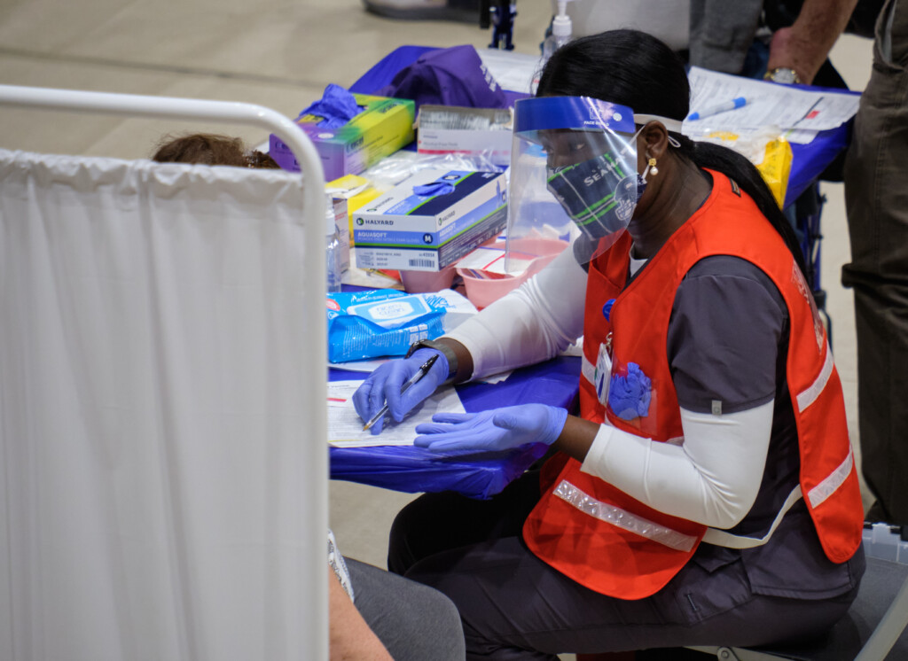 A PLU student walks a patient through a medical form at the vaccine event.