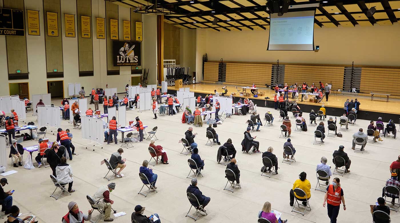 over a hundred health care professionals and community members spread out through PLU's Olson Gym. Some in an area to receive the vaccine, others filling out medical forms and waiting.