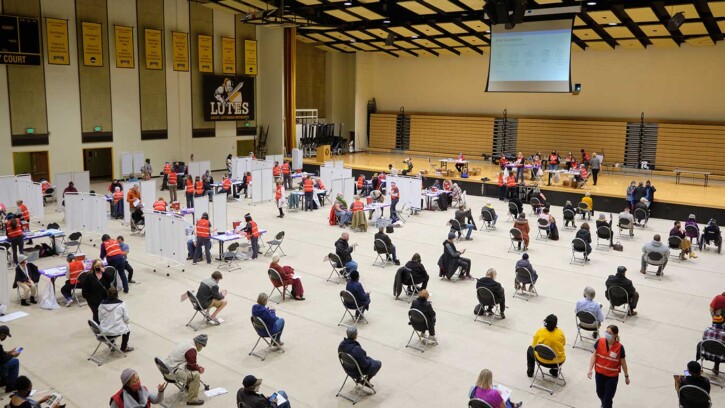 over a hundred health care professionals and community members spread out through PLU's Olson Gym. Some in an area to receive the vaccine, others filling out medical forms and waiting.