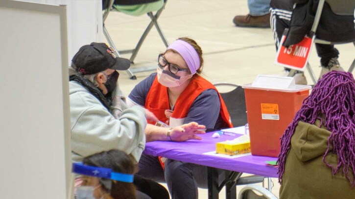 A PLU nursing student administers at a COVID-19 vaccine in PLU's Olson Gym.