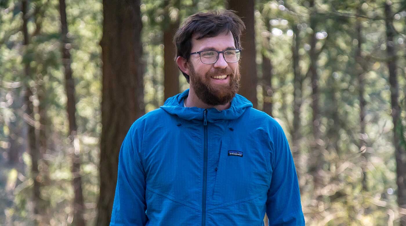 PLU alum and environmental advocate Andrew Schwartz wears a blue shell jacket as he walks through Mount Tabor Park in Portland, Oregon.