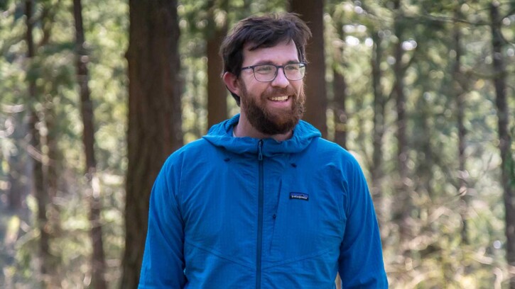 PLU alum and environmental advocate Andrew Schwartz wears a blue shell jacket as he walks through Mount Tabor Park in Portland, Oregon.