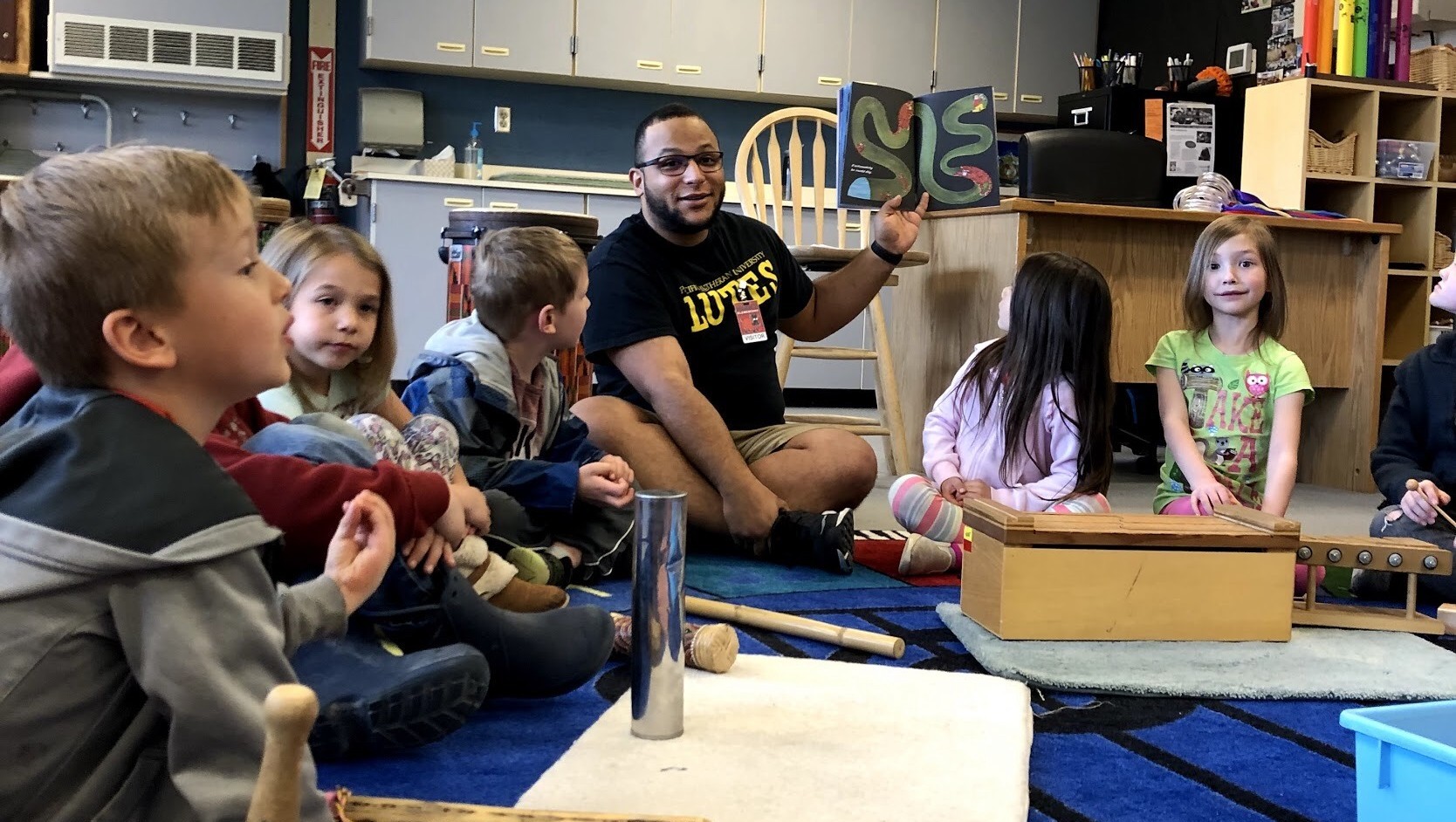 Elementary students sit in a circle focusing on their teacher