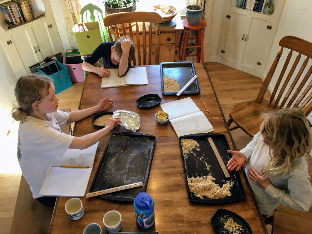 Sarah Lord_s table-referenced in story Photo of three children studying and doing homework on kitchen table.
