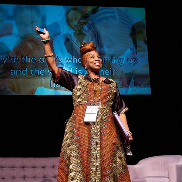 People's Gathering host and founder Melannie Denise Cunningham waves at the attendees from on stage at Karen Hille Phillips Hall.