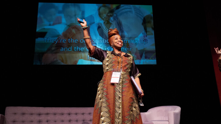 People's Gathering host and founder Melannie Denise Cunningham waves at the attendees from on stage at Karen Hille Phillips Hall.