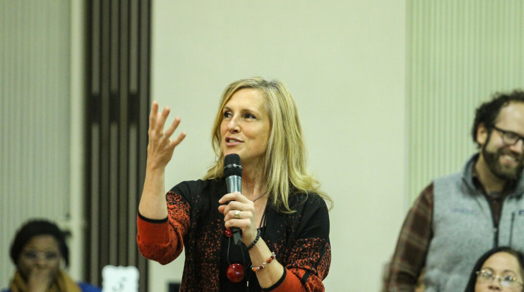 Kristy Gledhill holds a micrphone while speaking from the audience at a People's Gathering event