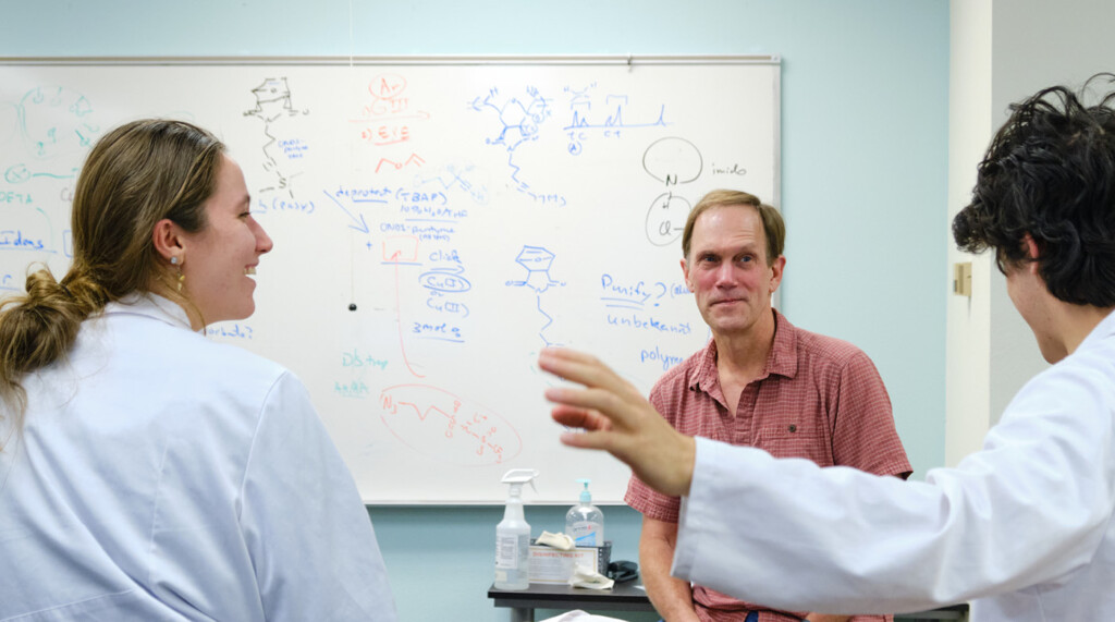 Professor Waldo talks with two students in a classroom.