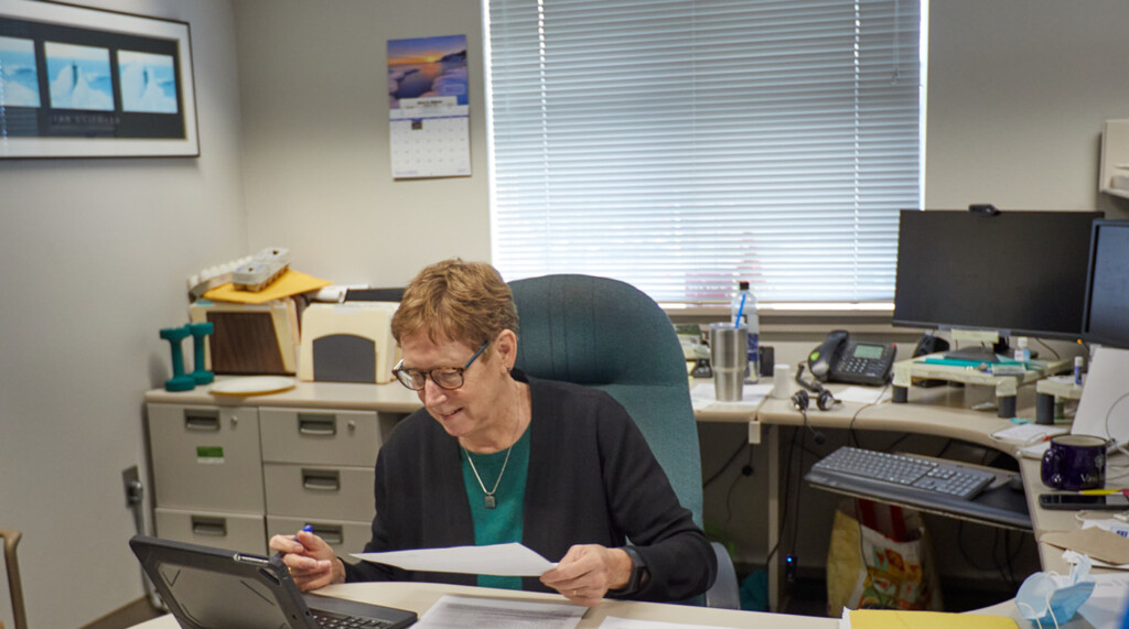Teri Card sits at her desk in her office looking over a document