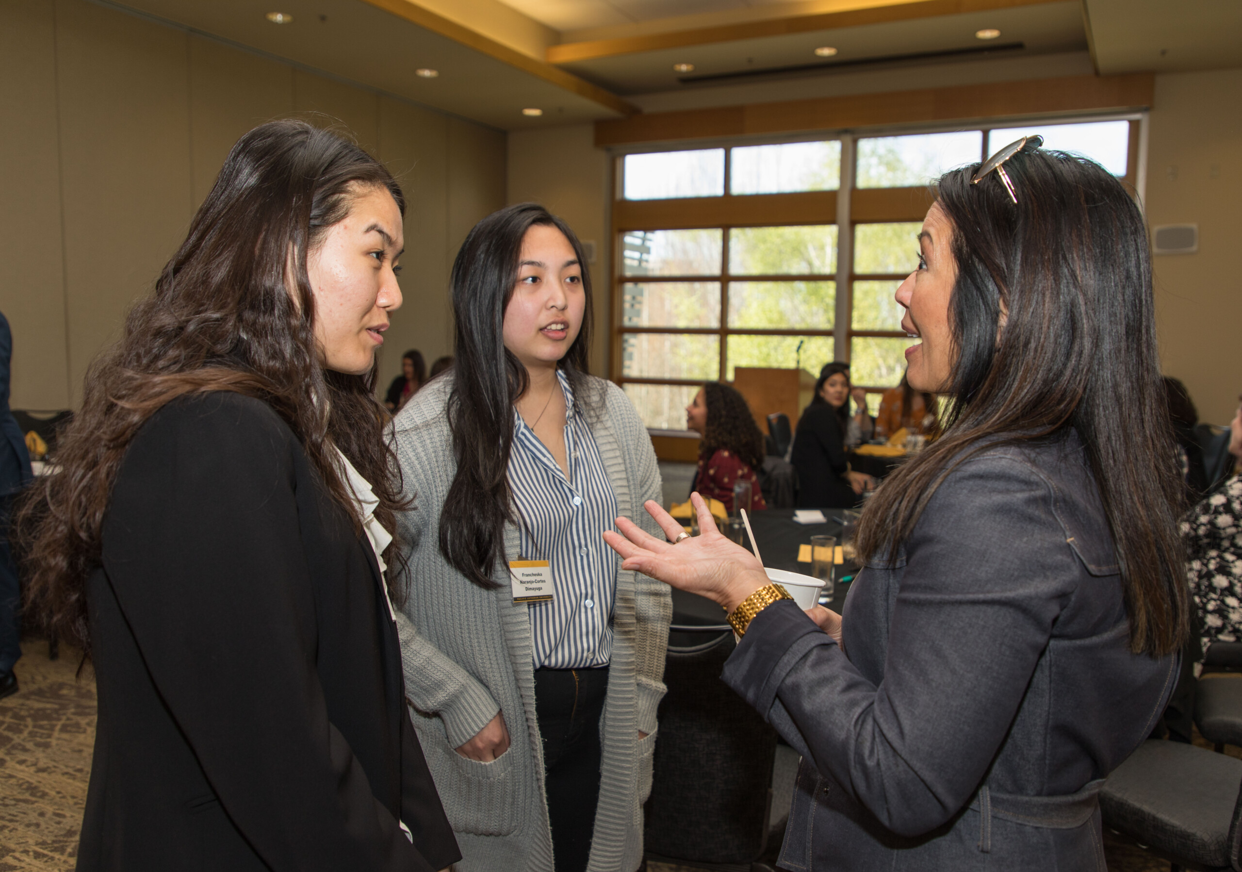 PLU alumni and current students talk in a three-person group at a mixer event held at Alaska Airlines' Corporate Office.