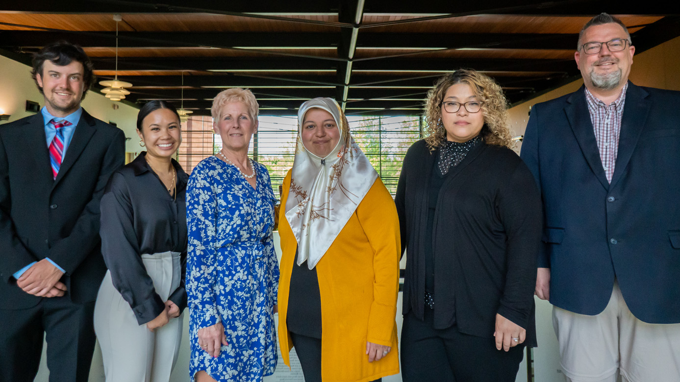 PLU school of business students and faculty members Melanie Brisbane ‘21, Mark Mulder, Alissa Ouanesisouk ’21, Cosette Pfaff, Ryan Pearson ’21, and Somaye Ramez standing up and down the stairs dressed in business attire in PLU’s Morken Business Center.