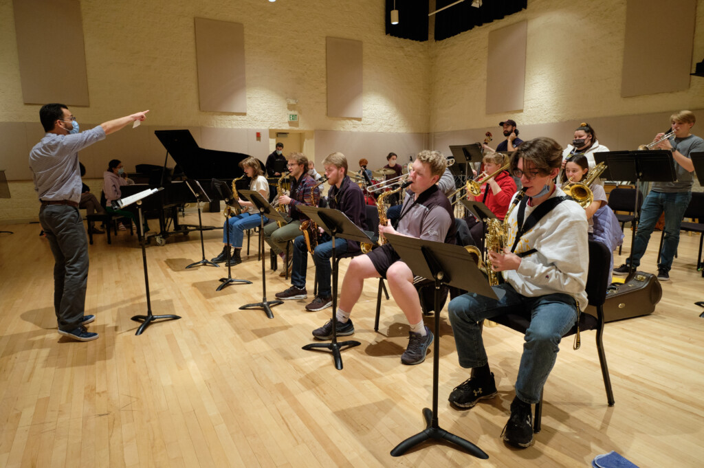 A photo of jazz ensemble practice, it's a wide photo of Cassio and all of the students mid-song.