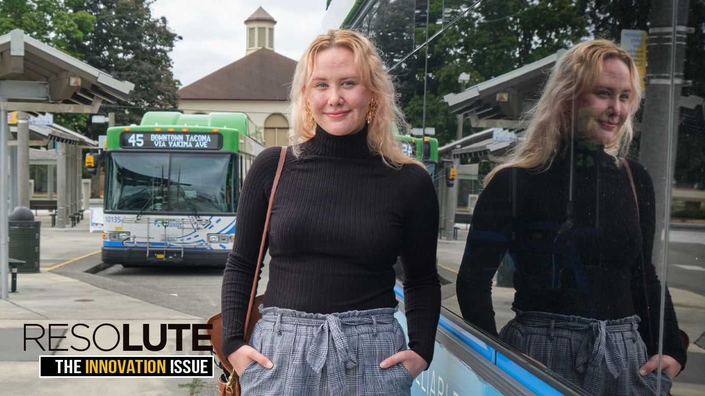 Kenzie posing for a portrait with a public transit stop in the background