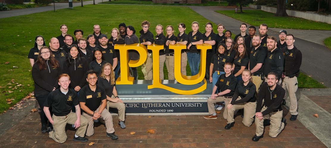 Campus Safety team photo around the large gold "PLU" sign
