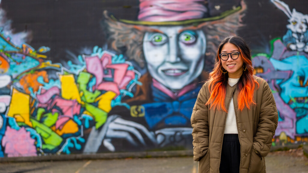 Gines stands in front of a downtown tacoma musical of the mad hatter from 'alice in wonderland'