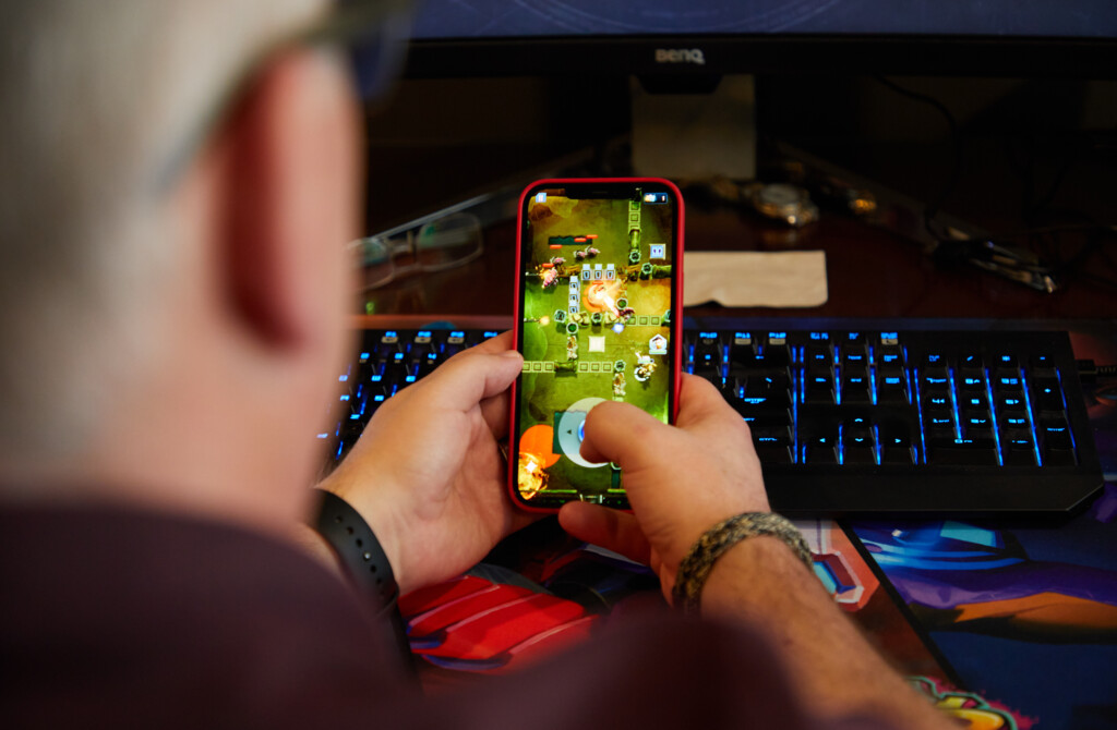 A close up of Grande's hands holding his phone as he plays a mobile game he's helped develop at Amazon.