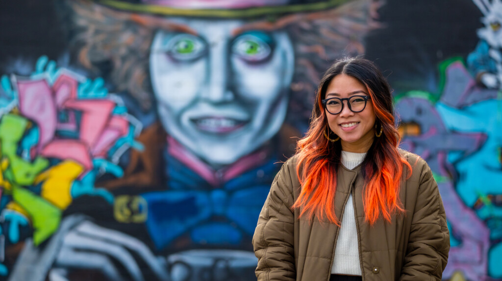 Clarissa Gines stands in front of a Mad Hatter mural in Tacoma, WA