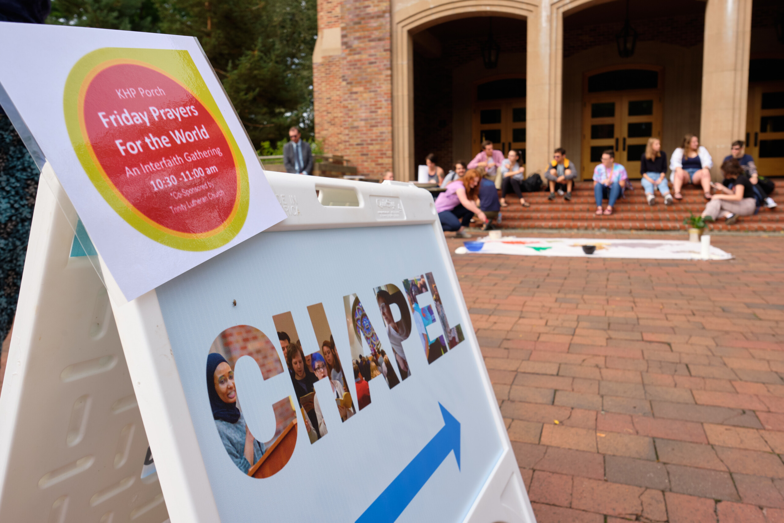 A sign on a sandwich board with a chapel sign on it pointing toward Karen Hille Phillips hall on PLU's upper campus