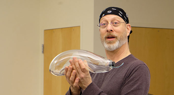 PLU IHON professor Daniel Heath holding a blown glass structure