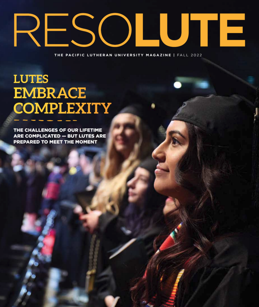 A student in fall graduation regalia looks up the commencement stage at 2022 PLU commencement at the Tacoma Dome.