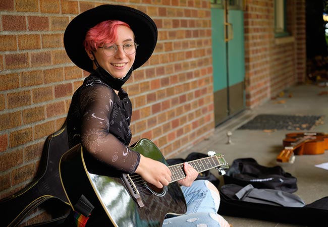 Ashton Allen ’25, music education major with a high school band focus teaches guitar to campers.