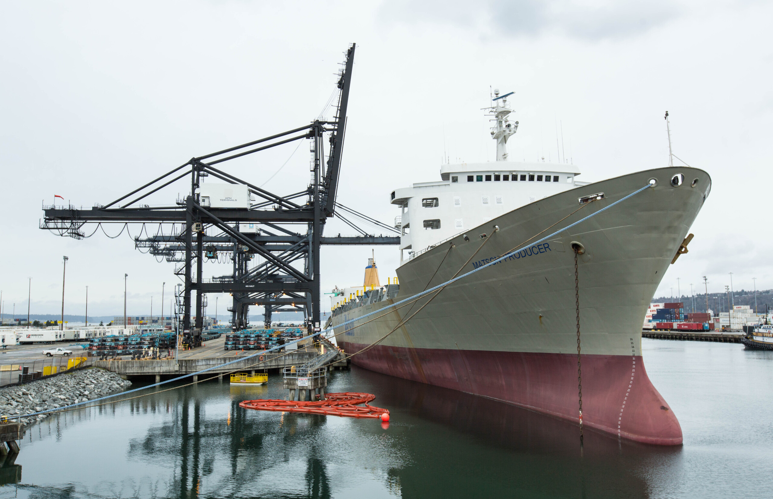 A large shipping port docked at the port to be unloaded or loaded by cranes and longshoremen.