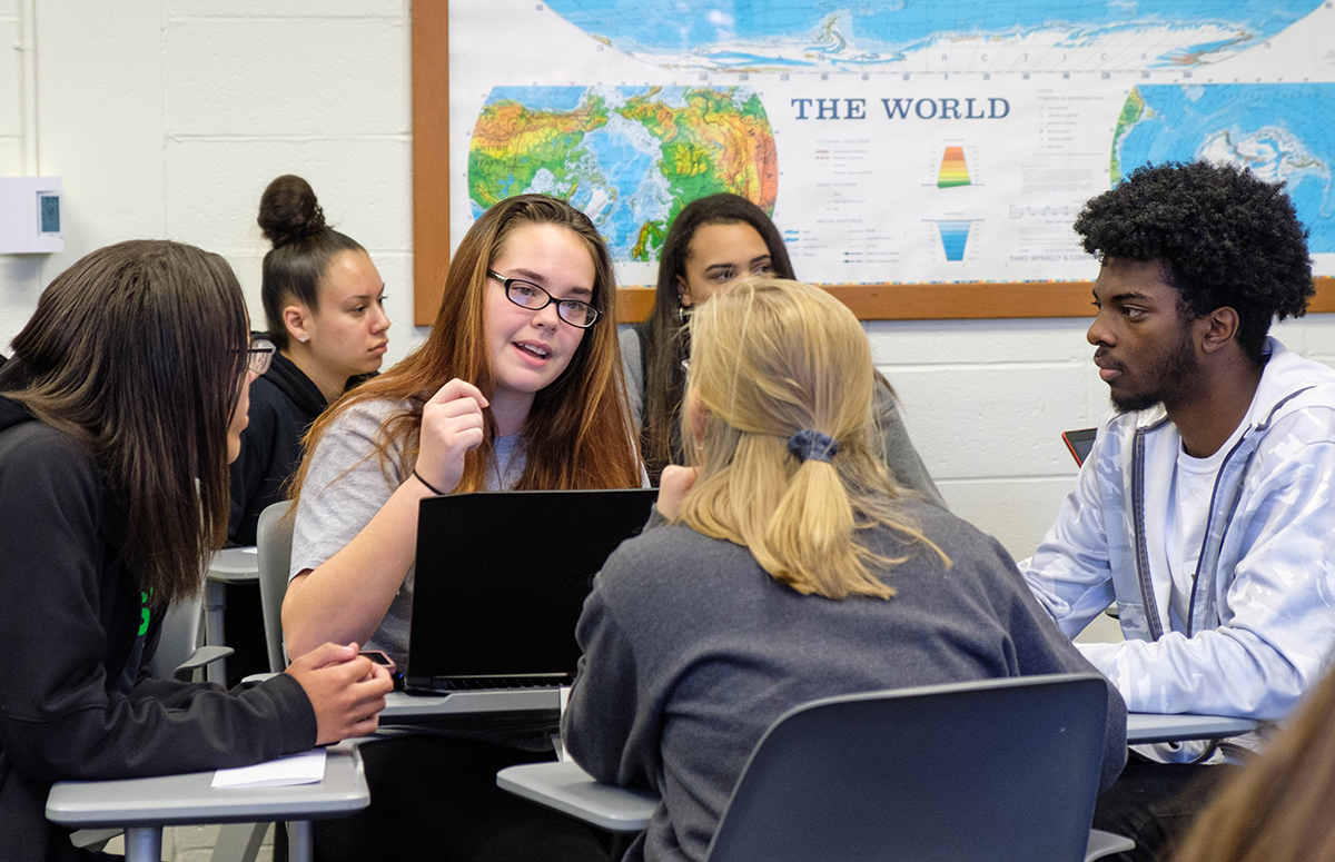 A group of students studying and discussing topics in a classroom setting.