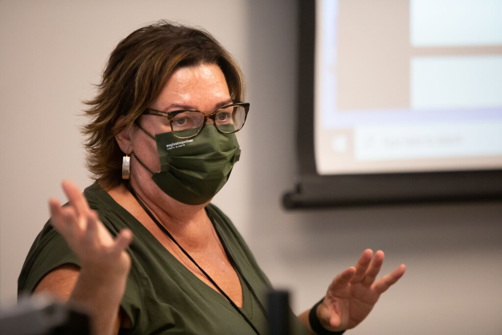 20220913_SB_Holocaust-Class-Beth-Polelle_012 Professor Lisa Marcus, wearing an olive green protective mask and shirt, giving instructions at the front of the class.