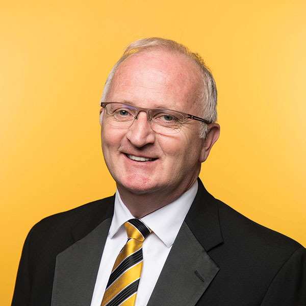 headshot photo of PLU President Allan Belton set against a solid gold background