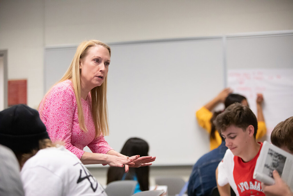 Holocaust-class-Beth-GP Beth Griech-Polelle leans in to talk to a table of students.