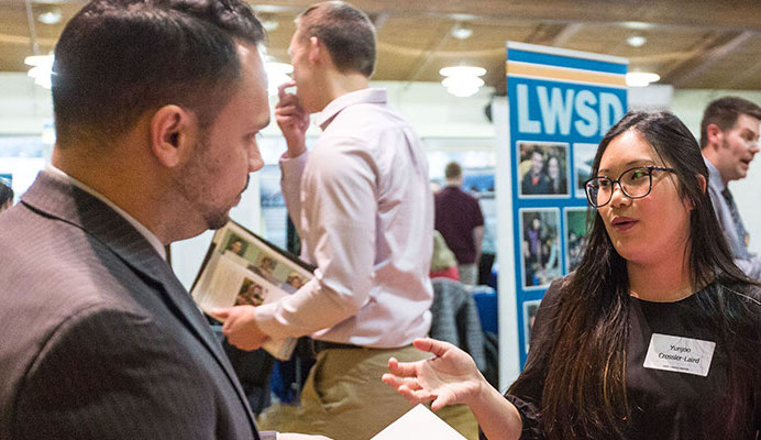 Two people are having a conversation during a career fair.