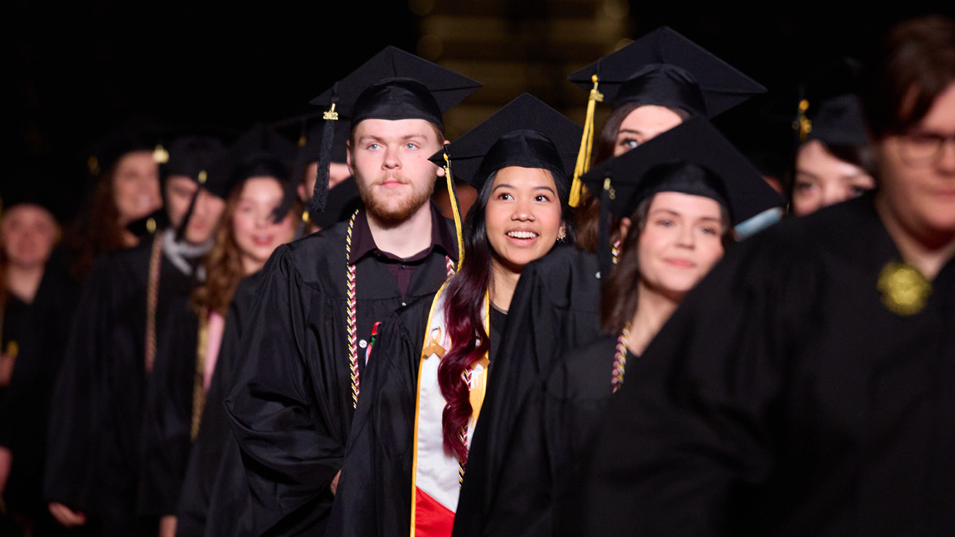 PLU seniors smile as they walk to their seats at the 2022 commencement ceremony at the Tacoma Dome.