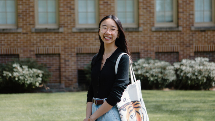 Tiffany Wong smiles into the camera with a brick campus building behind her.