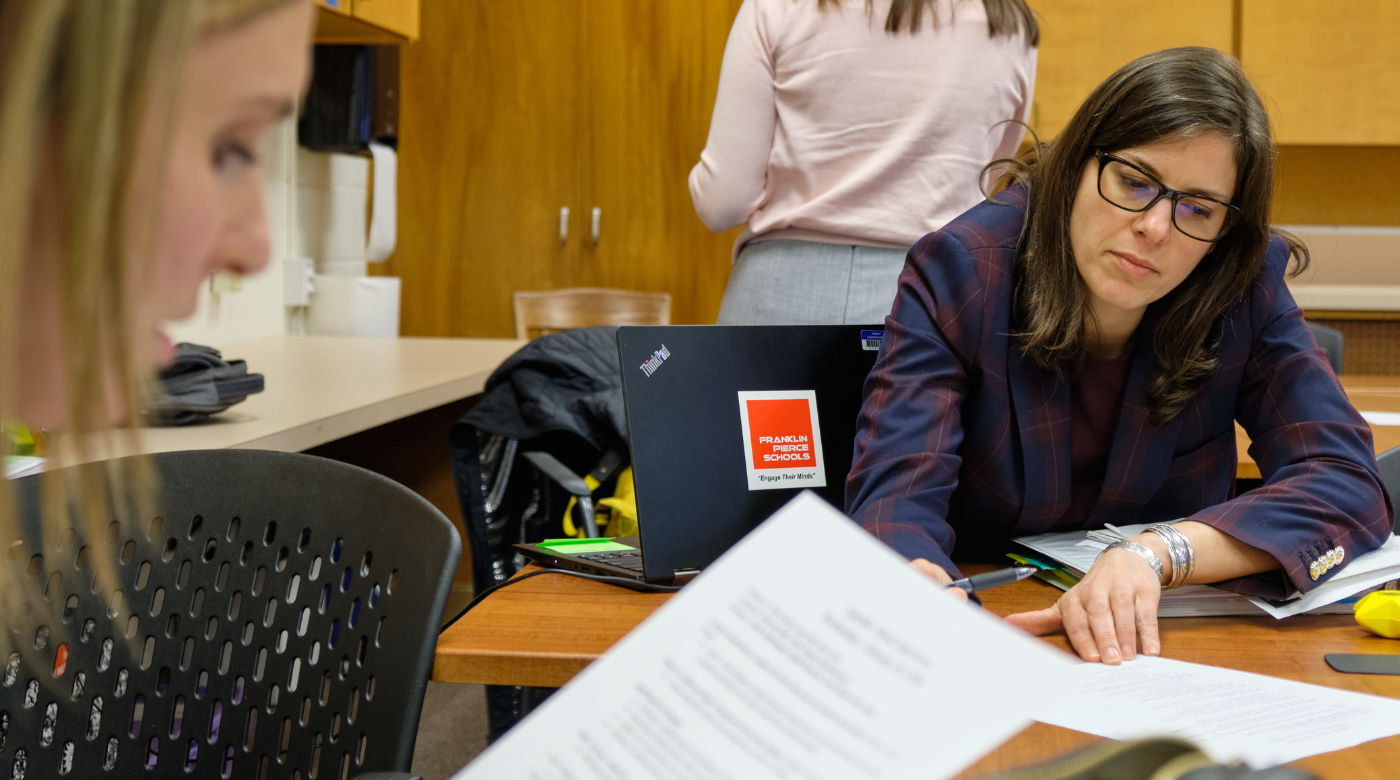 Two PLU student work together while sitting at a table reviewing paperwork. One student has dark hair and glasses the other is blond.