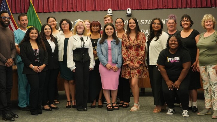 A group of high school student stand together in two rows looking into the camera and smiling.