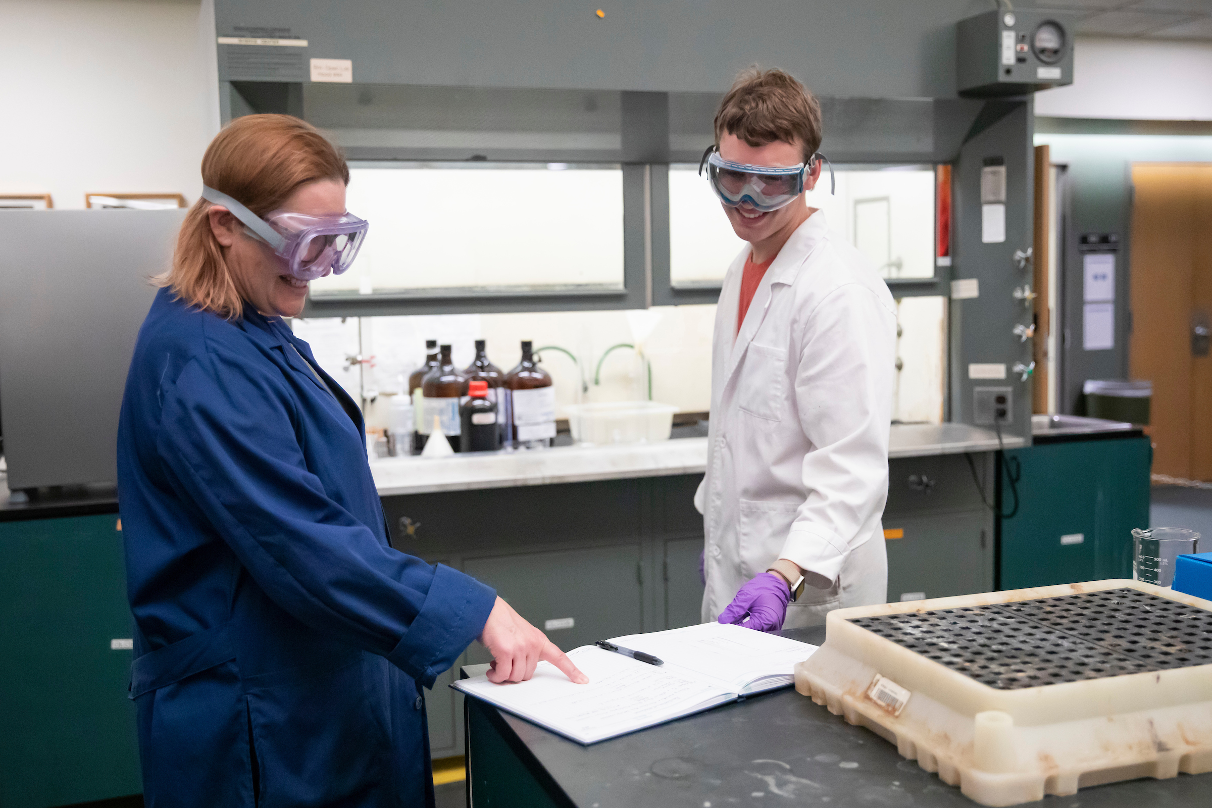 A PLU professor and student make a discussion over a lab notebook.