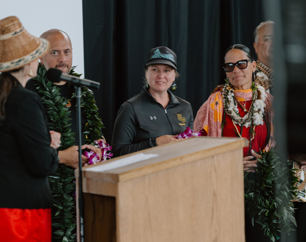 PLU Diversity Center Director Nicole Juliano smiles toward a speaker from the Puyallup Tribe who is standing at a podium.