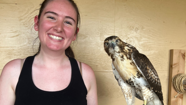 PLU Student smiles looking into the camera holding a hawk