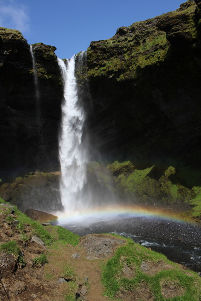 IMG_0557 (1) A photo of a waterfall with a rainbow where the falling water hits the water.