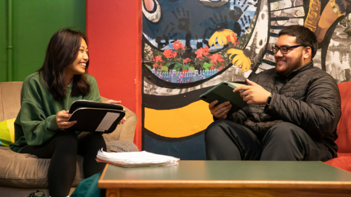 Two students talk to each other holding ipads.