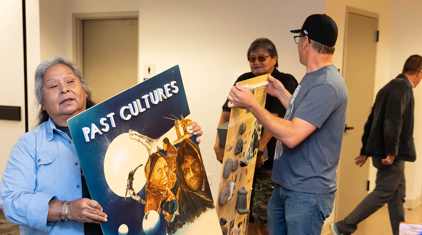Annette Bullchild (Nettsie), the Nisqually Tribe’s historic preservation officer, (pictured left) carries a poster from the Woodard Collection out of Xavier Hall.