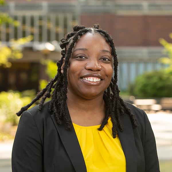 Teranejah Lucas smiling and wearing a black coat and yellow top.