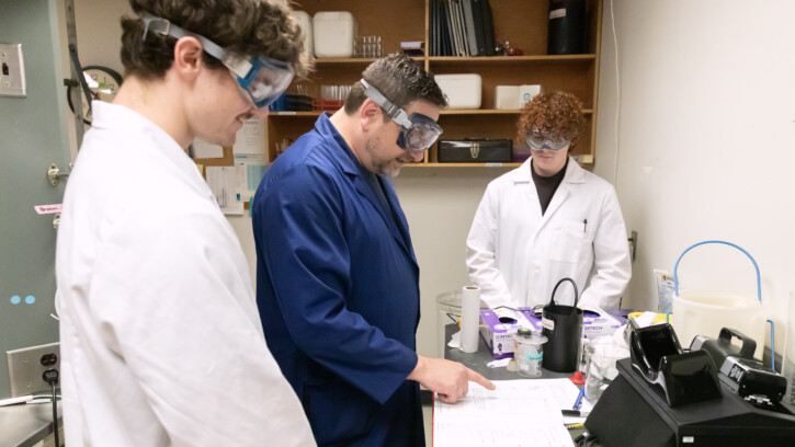 PLU students and professor reading lab notes in a lab.