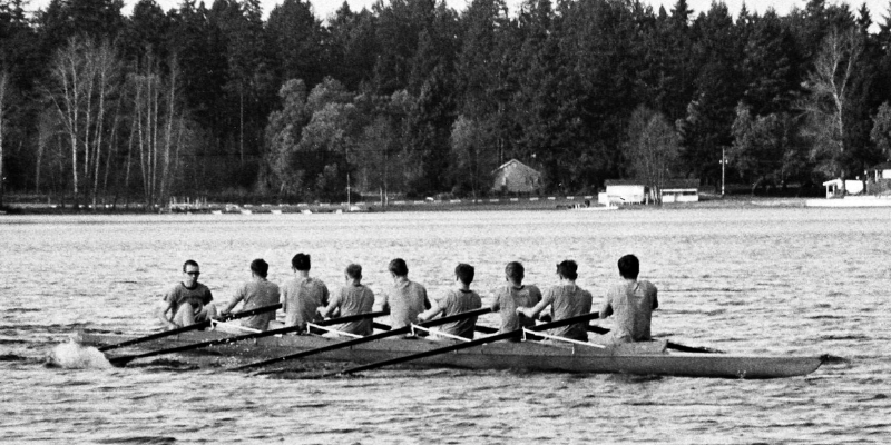 A black and white photograph of rowers rowing on a lake.